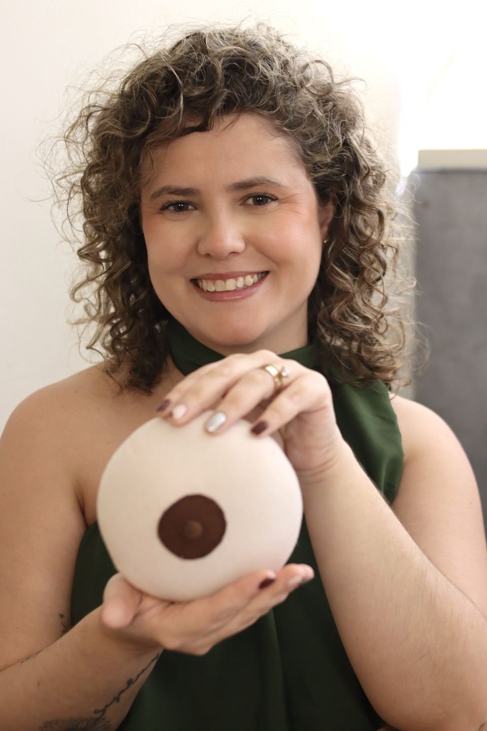 Laís Almeida demonstrando pega e posicionamento com um modelo didático de mama durante consultoria de amamentação.