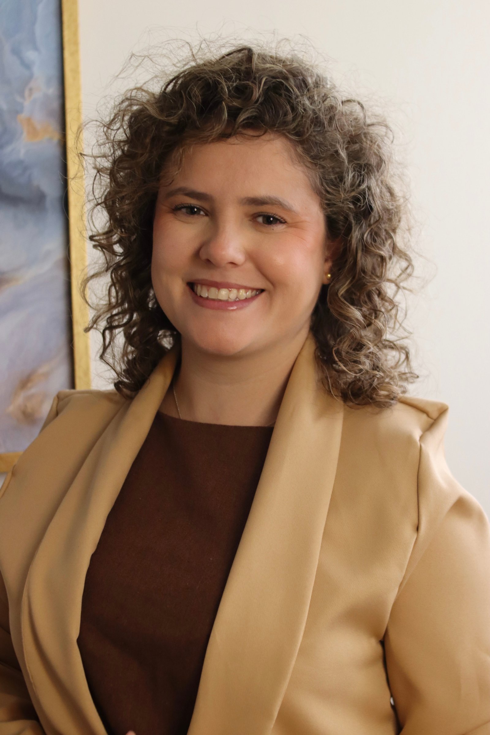 Laís Almeida, doula e consultora de amamentação, sorrindo em pé no consultório.